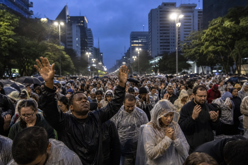 Evento “Amanhecer” reúne cristãos para oração e louvor antes do nascer do sol em São Paulo Cristãos reunidos ao amanhecer para oração e louvor em uma avenida ampla de São Paulo, sem textos ou logotipos visíveis.